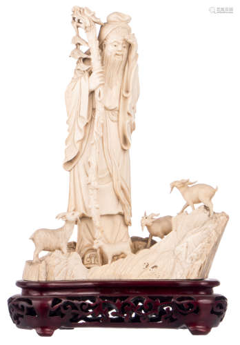 A Chinese group in carved mammoth ivory depicting a philosopher with goats on a rock, on a matching wooden stand, H 24,5 (without stand) - 29,5 cm (with stand) - Weight: about 1430g