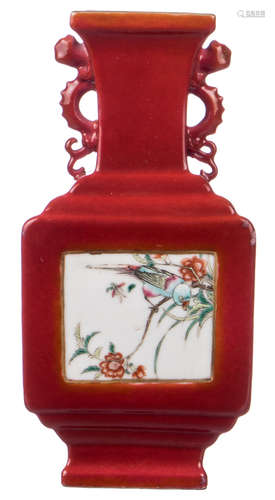 A Chinese quadrangular red ground baluster shaped vase, the roundels famille rose floral decorated, the handles dragon shaped, H 20 cm