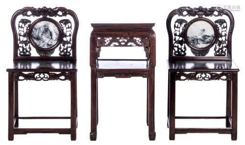 A pair of Chinese hardwood chairs carved with floral motives and bats, marble seat and back; added a ditto occassional table, carved with auspicious symbols, H 89 - W 48 - D 38,5 cm (chairs) and H 81 - 45 x 45 cm (table)
