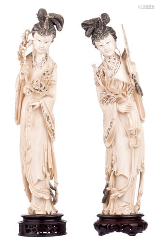 A pair of Chinese carved ivory figures depicting court ladies, first half of the 20thC, on a matching wooden stand, H 35 - 36,5 (without stand) - 38,5 - 40 cm (with stand) - Weight: about 1114 - 1191g