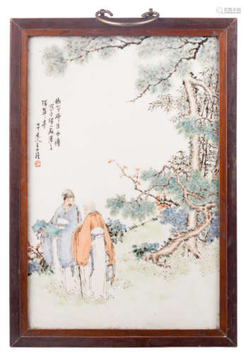 A Chinese polychrome decorated plaque with two figures in a landscape, with calligraphic texts, signed, in a wooden frame, 28,5 x 41,5 cm (with frame)