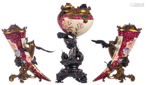 A three-piece garniture consisting of a cache pot carried by a triton, and two decorative horn shaped vases carried by dragons, polychrome decorated earthenware with gilt and silver plated mounts, late 19thC, H 35,5 - 47,5 cm