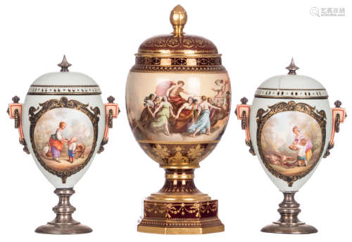 A pair of polychrome decorated biscuit chestnut vases, the roundels with animated scenes, (unsigned), mounted on a silver base, the covers with silver handles, mid 19thC; added a vase and cover in polychrome decorated porcelain, with mythological scenes, Vienna mark, the decoration signed Wagner, H 35 - 46 cm