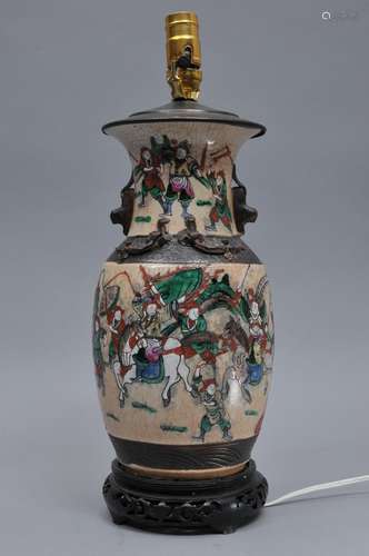 Porcelain vase. China. Late 19th century. Famille Rose historical scene on a cracked ground with unglazed brown borders and relief dragons and foo dogs. Drilled and mounted as lamp. 12-3/4