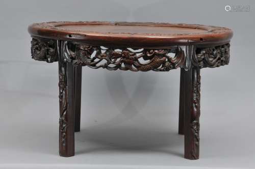 Hardwood table. China. Early 2oth century. Round top with four legs carved with grapes. Apron carved and pierced with dragons. 24-1/2