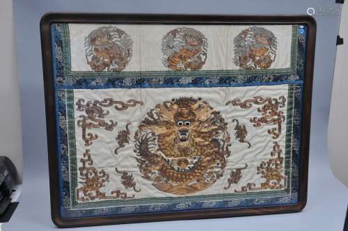 Embroidered silk panel. China. 19th century. Gold embroidery of dragons, foo dogs, bats and archaic scrolling on a white ground. Stains. Framed and glazed. 40