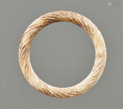 AN ORNAMENTAL RING IN PARTLY CALCIFIED WHITE JADE DECORATED WITH THE “TWISTED ROPE” PATTERN