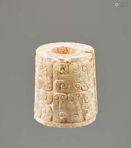 AN INTERESTING THICK EARRING OF THE JUE TYPE IN PARTLY CALCIFIED WHITE JADE DECORATED WITH STYLIZED DRAGON HEADS