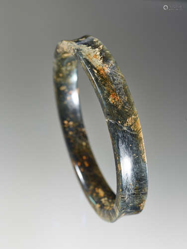 A DELICATE BRACELET IN DARK GREEN JADE WITH YELLOW-COLOURED SPECKLES AND A SMOOTH CONCAVE BORDER