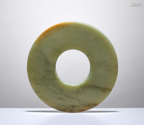 A SMOOTHLY POLISHED BI DISC WITH SHINY SURFACES CARVED FROM GREEN JADE WITH BROWN STRIPES