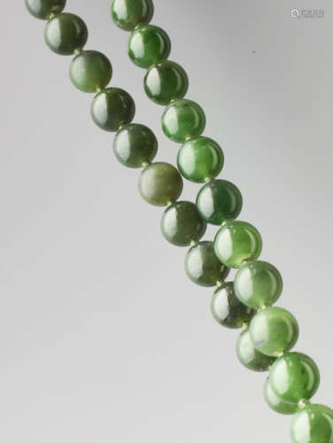 A SPINACH GREEN NEPHRITE BEAD NECKLACE, 71 BEADS, LATE QING DYNASTY