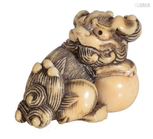 Ω A Japanese Ivory Netsuke, carved in the form of a seated Shishi