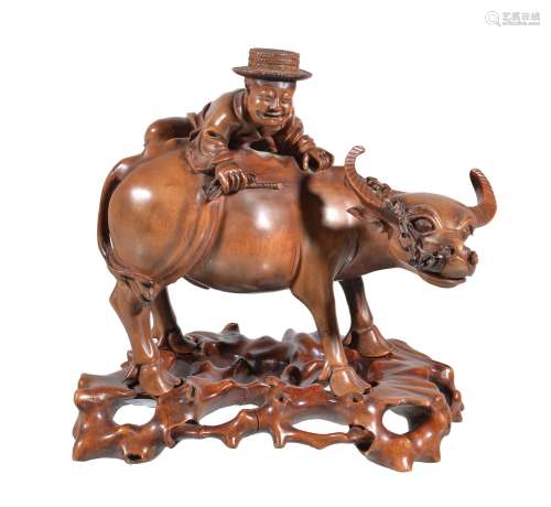 A Chinese carved wood model of a man climbing onto the back of a water buffalo