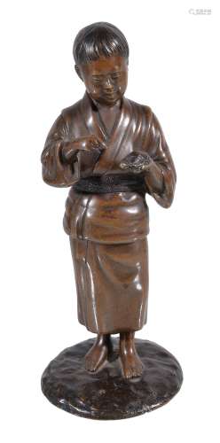 A Japanese Bronze Figure of a Boy, he stands on a textured circular base...
