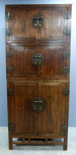 Chinese hardwood three section cupboard with panelled doors, the lower section with eight enclosed drawers, on square supports, 207cm x 89cm x 57cm,