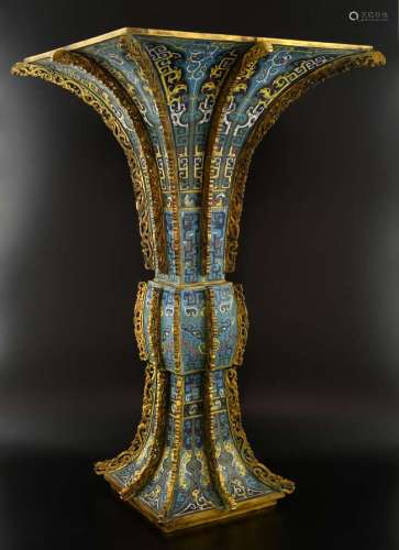 Chinese cloisonne vase of Gu form and square section, the blue ground decorated with archaic masks, flowers and scrolling decoration, the gilt metal mounts with pierced and scrolling decoration, bearing Qianlong four character mark to base, 54.5cm hi