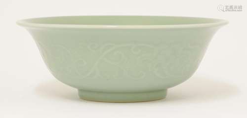 A celadon bowl, of circular form with shallow well and flared mouth, moulded with scrolling ...