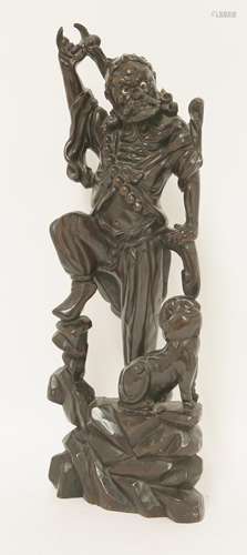 A Chinese wood carving, of an immortal with fierce expression, his right arm raised as he grapples ...