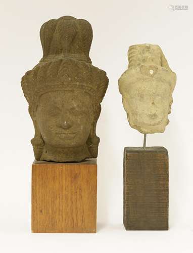 Two stone carvings of heads of a bodhisattva, Cambodian, each wearing a tall hat with jewels, ...