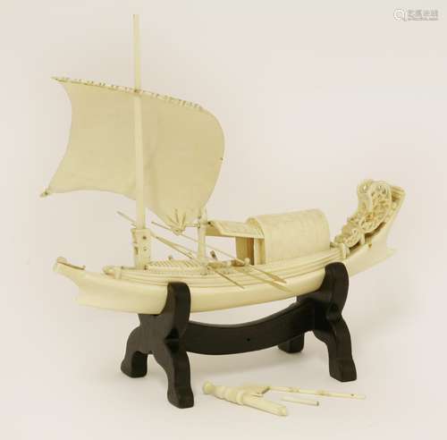 A Chinese ivory junk boat, c.1900, carved in details with a sail and cabin, paddles to the sides, ...