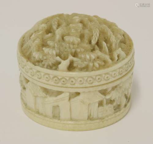 A Chinese ivory circular box and cover, late Qing dynasty, deeply carved with figures in a garden, ...