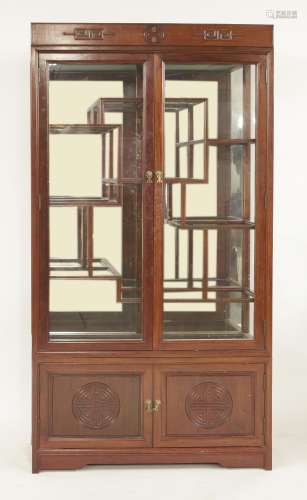 A Chinese cabinet, 20th century, with two hinged doors carved with shou roundels, below a series of ...