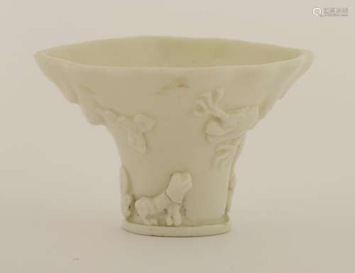 A Chinese blanc de Chine libation cup, 17th century, of rhinoceros form, moulded with a deer ...
