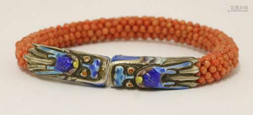 A Chinese bracelet, 1930s, with coral beads on a spring core, the terminals enamelled with dragon ...
