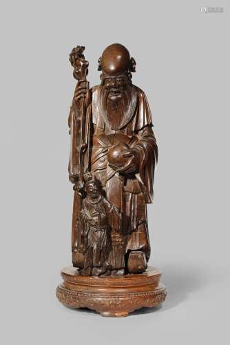 A LARGE CHINESE HARDWOOD CARVING OF SHOULAO LATE QING DYNASTY Standing, supporting himself on a tall