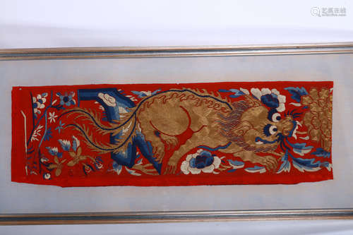 A CHINESE RED GROUND GOLD THREAD TEXTILE FRAGMENT DEPICTING A BUDDHIST LION DOG. Qing Dynasty.