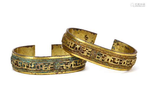 A PAIR OF CHINESE GILT BRONZE BRACELETS. Each with pierced rectilinear patterned designs, 9cm