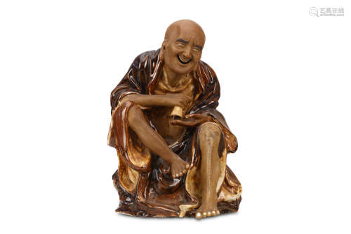 A CHINESE PORCELAIN MODEL OF A SEATED LUOHAN. Republican era. Seated on a rocky base, the legs