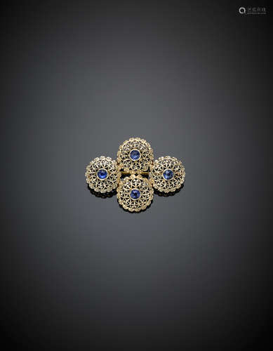 White and yellow gold openwork brooch in the shape of four buttons centered by four round synthetic sapphires, g 5.49, length cm 3.50 circa.