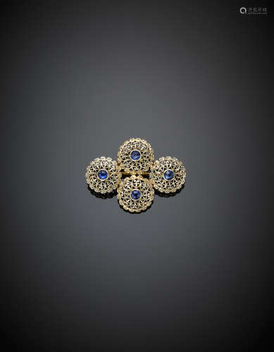 White and yellow gold openwork brooch in the shape of four buttons centered by four round synthetic sapphires, g 5.49, length cm 3.50 circa.