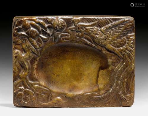 A MOTTLED BROWN INKSTONE CARVED WITH A PHOENIX AND FLOWERS.