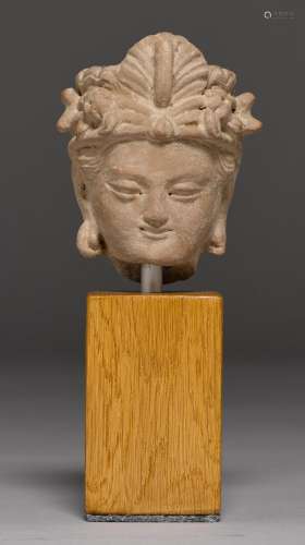 A SMALL TERRACOTTA BODHISATTVA HEAD. Gandhara, ca. 6th c. H 7.5 cm. Mounted on a plinth.