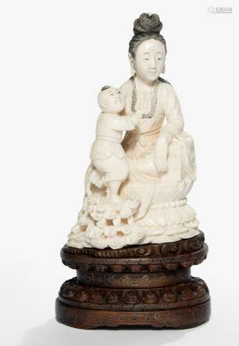 A FINELY CARVED IVORY MODEL OF SEATED GUANYIN AND BOY ON A SILVER-WIRE INLAID CARVED HARDWOOD STAND