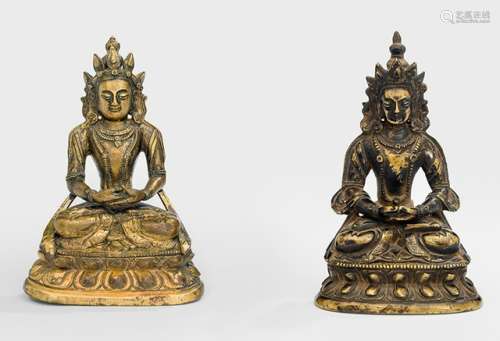 TWO PARTLY GILT-BRONZE FIGURES OF AMITAYUS, Tibeto-Chinese, 18th/19th ct., both seated in vajrasana on a lotus base with both hands resting in dhyanamudra on their laps, wearing dhoti, scarf and bejewelled, their faces displaying a serene expression with downcast eyes and their hair combed in a chignon secured with tiaras, the largest sealed and the other unsealed - Property from a German private collection, assembled in the 1970s and 80s - Wear, kalashas lost, very slightly chipped