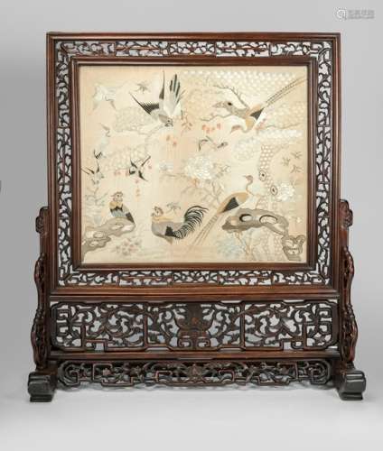 A FINE SILK EMBROIDERY PANEL DEPICTING BIRDS SET WITHIN A FRAME AND MOUNTED AS A SCREEN, China, late Qing dynasty - Fine embroidery using various techniques to depict naturalistic birds, the frame of the screen ant the stand made of carved openwork hardwood - Property from an old German industrialist collection, assembled between 1950 and 1990 - Stand slightly chipped, embroidery in good condition