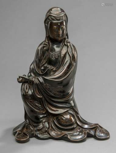 A SILVER INLAID BRONZE FIGURE OF GUANYIN, CHINA, marked xuande yuannian yutang shisou wujin zhizao (=1426), 17th/18th ct., seated in rajalilasana with both hands elegantly resting on a raised knee and holding a scroll, wearing various garments including a wide-sleeved mantle, inlaid with silver cloud-motifs, necklace, her face displaying a serene expression with downcast eyes below arched eyebrows running into her nose-bridge, her hair combed in a chignon and covered with a veil, the reverse with an archaic twelve character inscription, the base with a six-character mark Xuande - Property from a Dutch private collection - Very minor wear