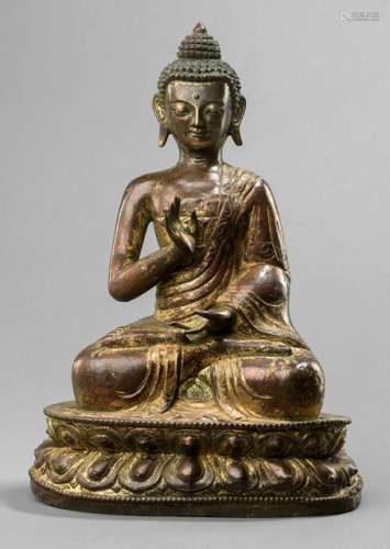 A GILT-COPPER EMBOSSED FIGURE OF BUDDHA SHAKYAMUNI, Tibet, 19th ct., seated in vajrasana on a lotus base with his right hand in abhayamudra while the left is resting on his lap, wearing a monastic garment, his face displaying a serene expression with downcast eyes, urna, his curled hair and ushnisha topped with a lotus-bud, unsealed - Property from the estate of a German private collector, assembled between 1970 and 2012 - Wear, base chipped