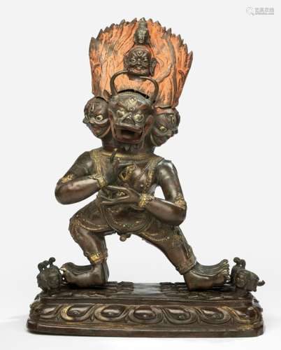 A PARCEL GILT-COPPER EMBOSSED FIGURE OF VAJRABHAIRAVA, Tibeto-Chinese, 19th ct., standing in alidhasana on various deities reclining on a lotus base, his principle hands originally holding karttrika and kapala, the others missing, ithyphallic, bejewelled, his nine faced head with central bull one and flaming red coloured hair-dress, unsealed - Property from a German private collection, bought in the 1970s - Arms partly lost, slightly chipped