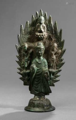 A STANDING BRONZE FIGURE OF BUDDHA SHAKYAMUNI WITH A FLAMING MANDORLA, China, possibly Northern Qi dynasty, dated 571. The back of the mandorla with a devotional inscription and dated to the 2nd year Wuping, 571. Buddha Shakyamuni dressed in a flowing robe with many folds, standing on a lotus base in front of a flaming mandorla, his right hand in abhayamudra, his left in varadamudra. His mandorla with accompanying bodhisattavas on pedestals. Above him probably an abbot. The small tongues of the flames symbolize the light rays of Buddha's appearance and teachings. - Former property from a German private collection - Cf. a Maitreya of similar style at Sotheby's N.Y., 21 Sep 2007, Lot 5; cf. an Avalokiteshvara of similar style at Sotheby's H.K., 5 Oct 2016, Lot 3211S - Strong, green patina, some of the flames' tips damaged, mandorla and base re-attached