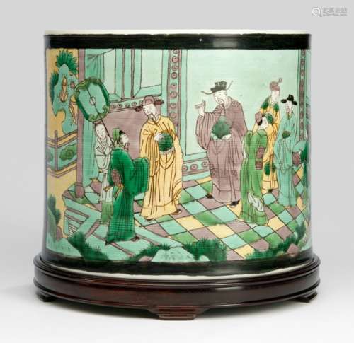 A FINE AND VERY RARE 'FAMILLE JAUNE' BRUSHPOT, Bitong, China, Kangxi period, of cylindrical shape, enamelled around the exterior with two panels in green, yellow, pale aubergine and black, one depicting a court scene with scholars, the other with scenes of courtly women and three deities, all reserved on a black background, the underside with a recessed circle - The enamel on these unusual brushpot is remarkably well preserved and retains the slightly iridescent quality that heightens their decorative nature . In their effort to revive biscuit wares, the Qing craftsman opted for the sancai glaze combination of amber-yellow ,green and brown instead of the turquoiseand purple palette of the fahua tradition ,which had gained much popularity in the Ming dynasty .This allowed for a fresh aesthetic that was suited to contemporaneous taste. Famille-jaune wares of such high quality are unusual; compare a globular vase with handles, in the Benaki Museum ,Athens , illustrated in Leigh Ashton and R.L.Hobson ,Catalogue of the Chinese Pottery & Porcelain, Athens ,1939 ,pl .XXXIX ,no .595 - Property from an important European private collection, bought from Christie's London, 9.11.2010, Lot 322 - Good condition, hardwood stand