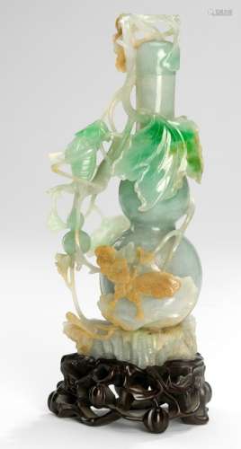 A FINELY CARVED JADEITE GOURD-SHAPED VASE WITH CRICKET AND BUTTERFLY, LEAFS AND GOURDS, China, late Qing/Republic period - Property from an old Italian private collection, assembled prior 1990 - Few tiny chips, carved wood stand