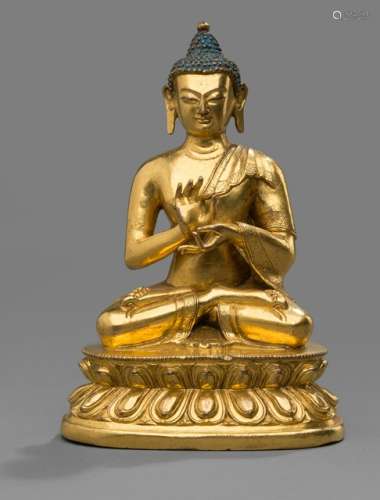 A GILT-BRONZE FIGURE OF BUDDHA SHAKYAMUNI ON A LOTUS BASE, Tibeto-Chinese, 18th ct. The Buddha seated in vajrasana with his hands in dharmachakramudra, his face showing a serene expression with downcast eyes, his hair coiffed into an ushnisha with blue painting. - Property from a German private collection, acquired in the 1960s and 70s - Very silightly chipped, minor wear