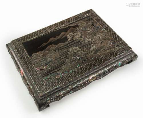 A MOTHER-OF-PEARL INLAID LACQUER STAND, China, Kangxi period. Finely inlaid in slivers of iridescent mother-of-pearl with a landscape depicting several pavilions scattered on rocky shores interlinked by arched bridges and lined with a variety of trees and a waterfall, with three flat-bottomed boats drifting on rippling waters and the moon rising between misty mountains in the distance, the apron detailed with clusters of chrysanthemum flanked by sprays of camellias within meander and cloud borders and fern leaves draping the legs. - Former property from an Austrian private collection - Cf. Sotheby's Hong Kong, 8 Oct 2013, Lot 166 - Some missing inlays, some age cracks, some chipping, some touch ups to the black lacquer around the feet - Minor wear