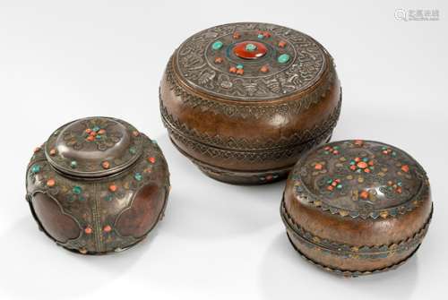 THREE BURLWOOD BOXES AND COVERS WITH SILVER FITTINGS AND STONE INLAYS, Mongolia, 19th ct. One box in the shape of a shouldered jar, with fine silver ornaments with polychrome painting and lobed cartouches accentuating the wood's grain. The second one with similar silver decor, showing more of the wood underneath. The largest box is adorned with thinly worked silver wire fittings, the top of the lid showing a detailed depiction of the Eight Auspicious Symbols of Buddhism, via a meandering band connected with several animals. - Property from an Austrian private collection, acquired before 2016 - Minor traces of age, minor age cracks to the wood