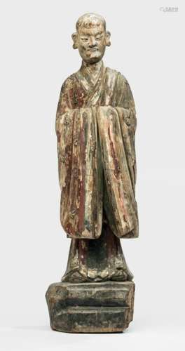A POLYCHROME WOOD FIGURE OF A MONK, CHINA, Ming dynasty, standing on a base with his head slightly bent downwards, both hands in front of the abdomen hidden by the wide sleeves of his mantle covering both shoulders and falling down in pleats, his face displaying a serene expression with slit eyes, smiling lips and bald head - Property from an important European private collection, bought 1971 from De Regaini, Paris - Minor damages and corrosion due to age, wear