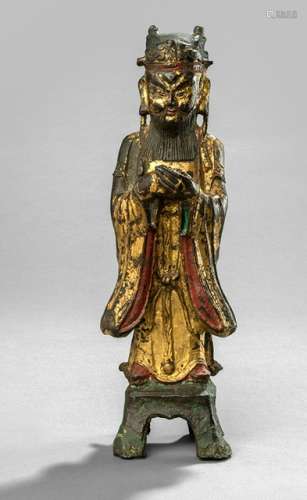 A GILT- AND RED-LACQUERED BRONZE FIGURE OF AN IMMORTAL, CHINA, 17th ct., standing on a pedestal on four legs, his hands clasped in front of his breast, wearing various garments, his face displaying a stern expression with raised eyebrows, long beard and moustache framing his mouth and his head topped with a cap - Property from an old Dutch private collection, assembled from 1950 till the 1990s, by descent to the present owner - Wear, sceptre lost